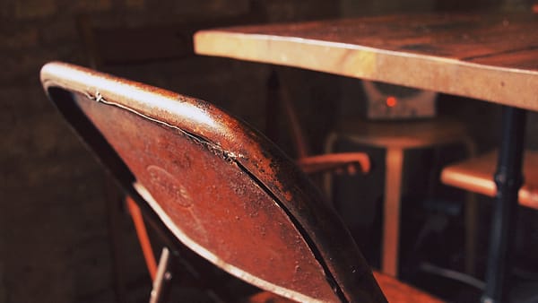 A single chair drawn up to a table in an otherwise empty room