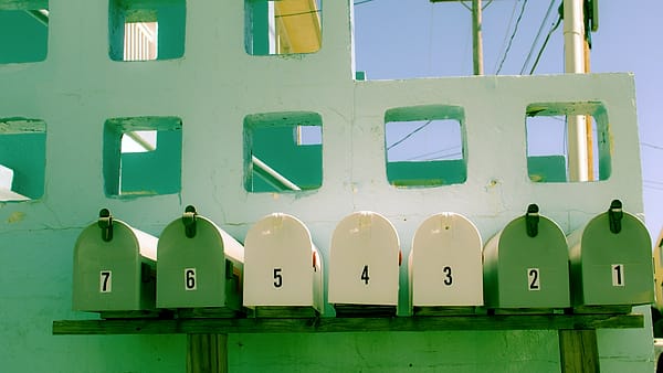 A bank of numbered residential mailboxes fixed side by side to an exterior wall