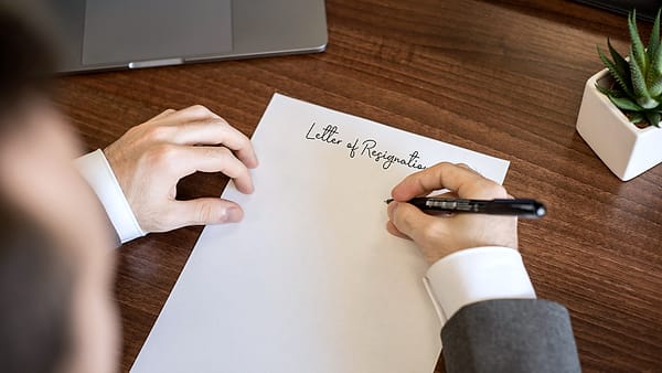 Somebody writing a short letter by hand on a sheet of paper at a table