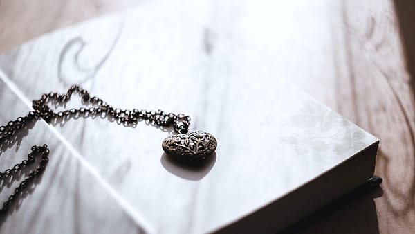 A small locket resting on the open pages of a book left face up on a table