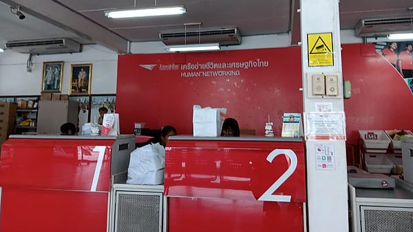 A post office counter with service windows and a queue rail running in front of it