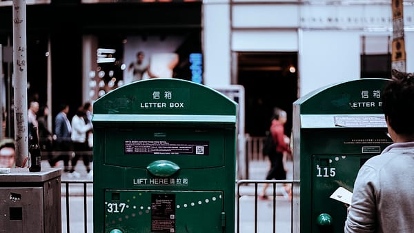 A public letter box standing at a street corner in flat daylight