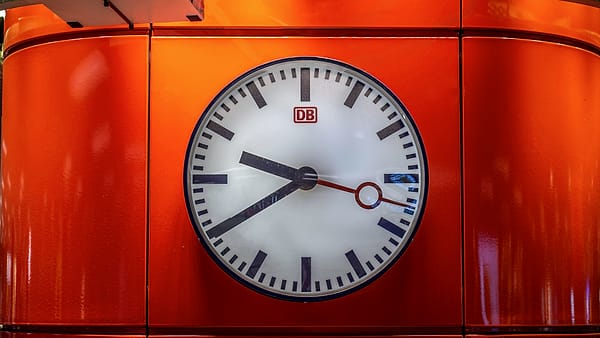 A large station clock hanging above a concourse, its hands clearly readable
