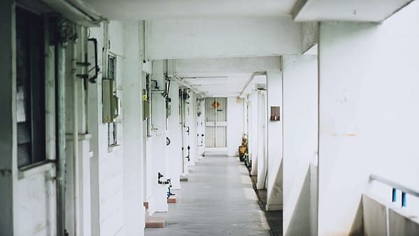 A long white corridor running away from the camera toward a distant end