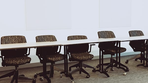 Empty office chairs pushed in around a long, bare conference table