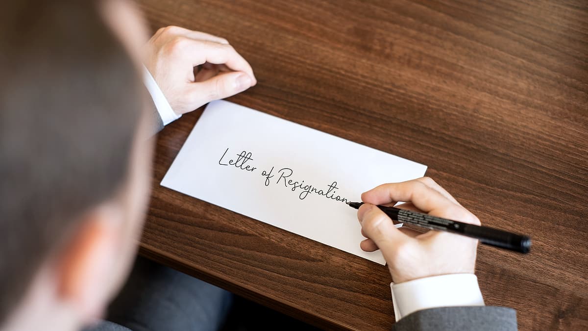 A handwritten letter lying on a desk beside a pen, its lines of script clearly visible