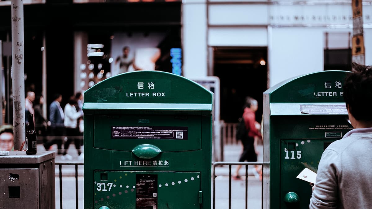 A wall-mounted letter box with a narrow slot, photographed against a painted wall