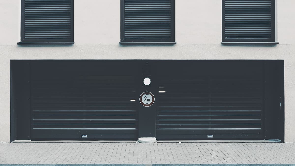 A metal shutter pulled fully down over an entrance beside a plain wall