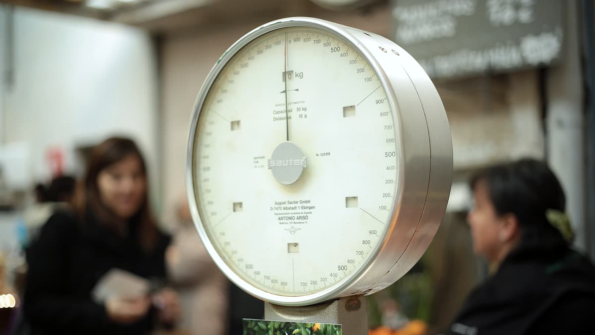 A set of old shop scales standing on a counter with its pan and dial visible