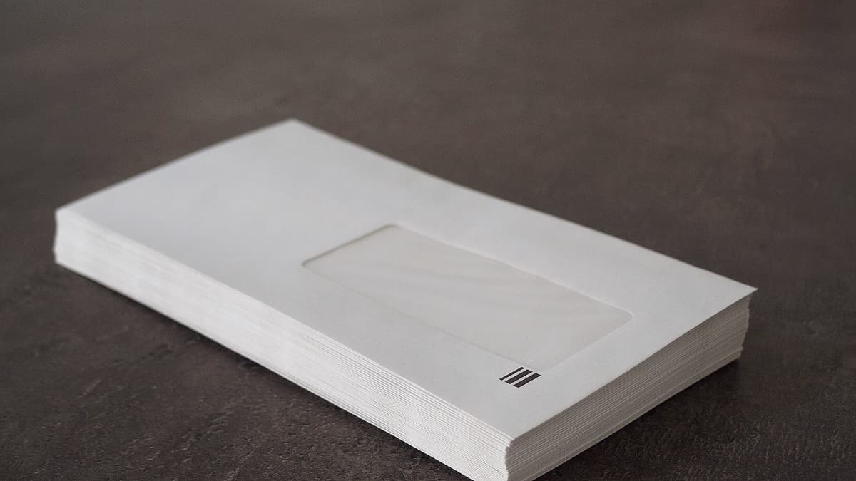 A stack of unopened envelopes squared up together on a plain flat surface