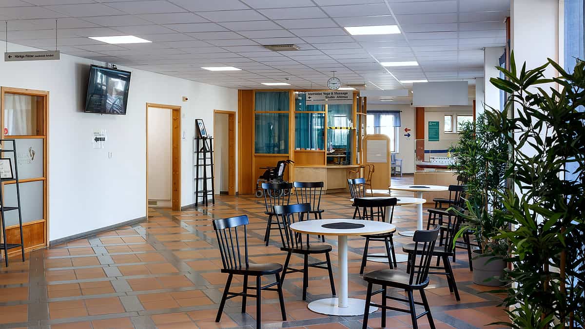 A public reception area with round tables and chairs and a corridor leading off it