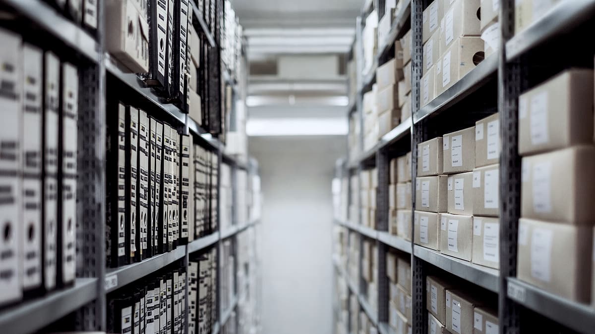 Rows of labeled archive boxes stacked on metal shelving in a storage room
