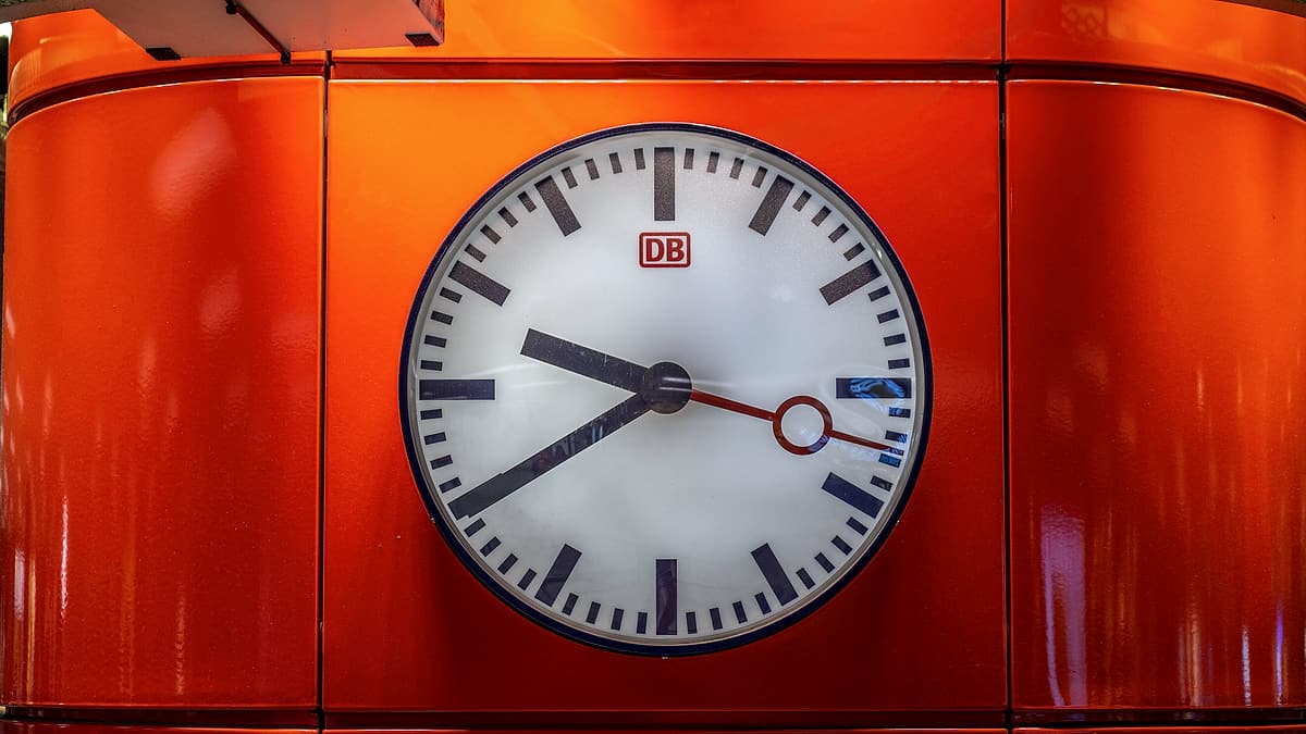 A large station clock hanging above a concourse, its hands clearly readable