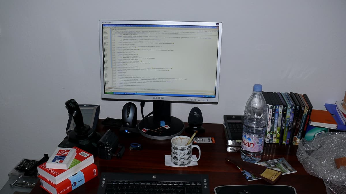 A cluttered working desk covered with papers, books and loose stationery