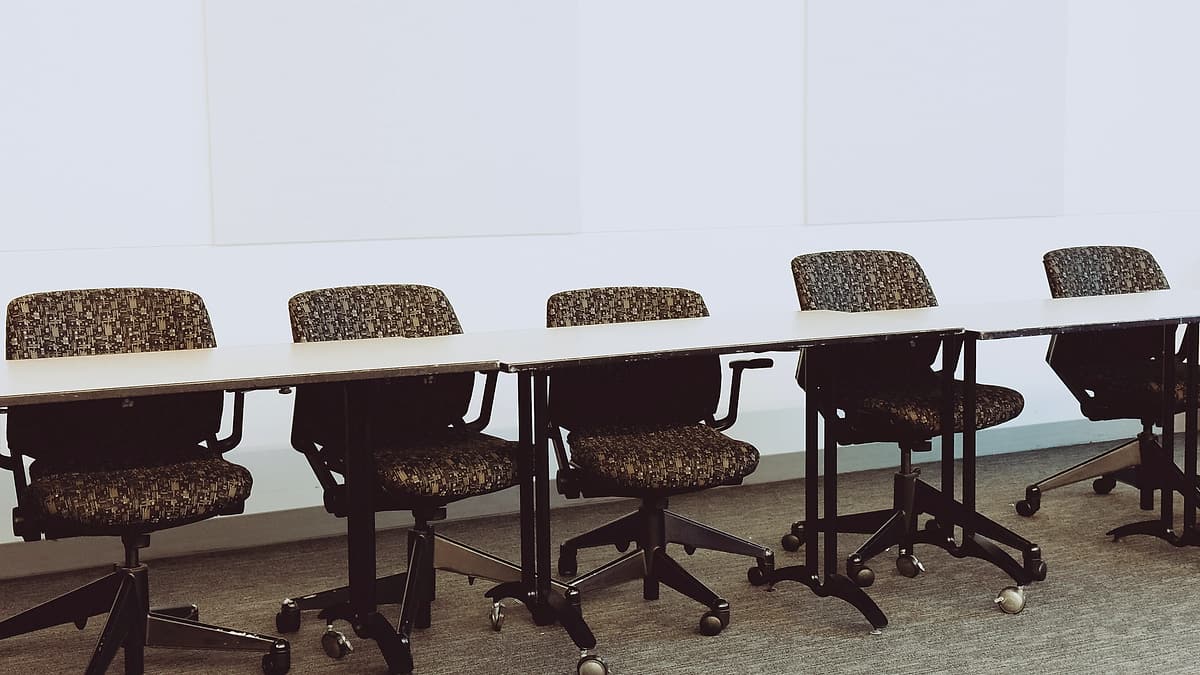 Empty office chairs pushed in around a long, bare conference table